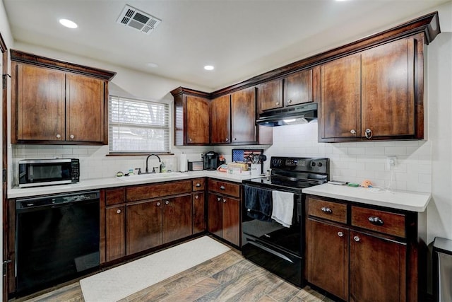 kitchen with dark brown cabinetry, sink, decorative backsplash, and black appliances