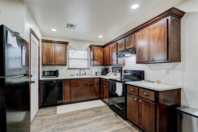 kitchen featuring light hardwood / wood-style floors, sink, dark brown cabinetry, and black appliances