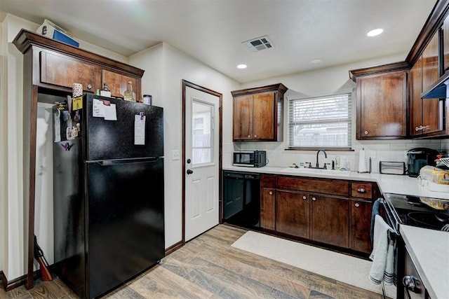 kitchen featuring dark brown cabinets, sink, light hardwood / wood-style flooring, and black appliances