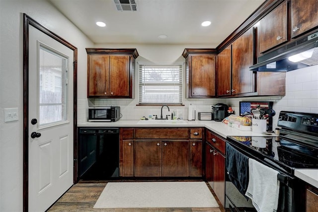 kitchen with sink, decorative backsplash, dark brown cabinets, and black appliances