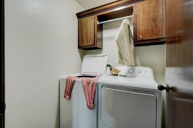 clothes washing area featuring cabinets and washer and dryer