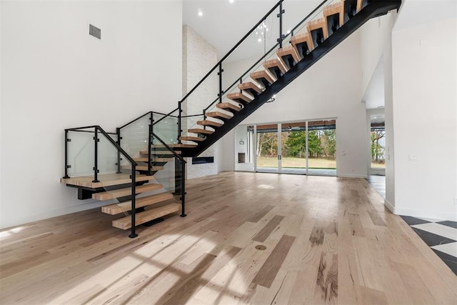 stairs with hardwood / wood-style flooring and a towering ceiling