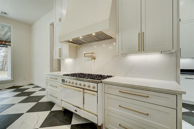 kitchen with custom exhaust hood, backsplash, white cabinets, and range with two ovens