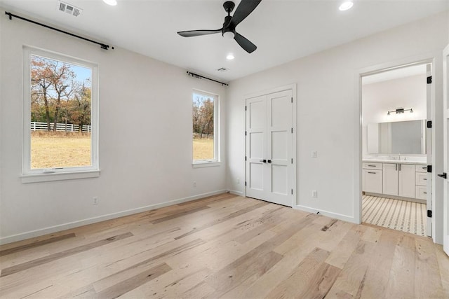 unfurnished bedroom with sink, ensuite bath, light hardwood / wood-style flooring, a closet, and ceiling fan