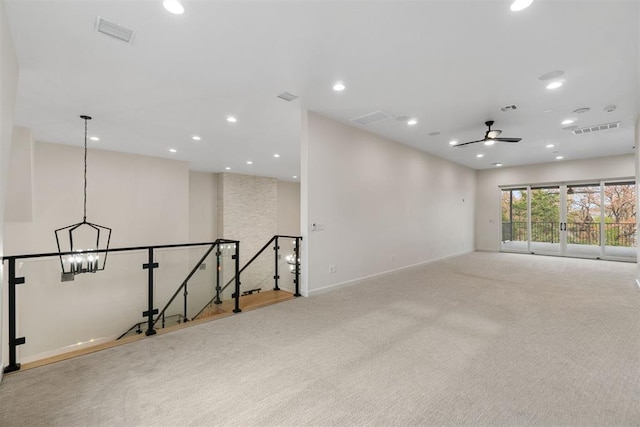 empty room featuring ceiling fan with notable chandelier and light colored carpet