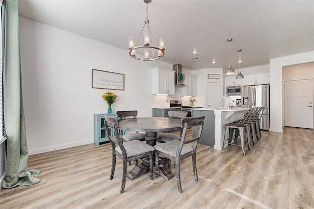 dining area with a chandelier, sink, and light hardwood / wood-style flooring