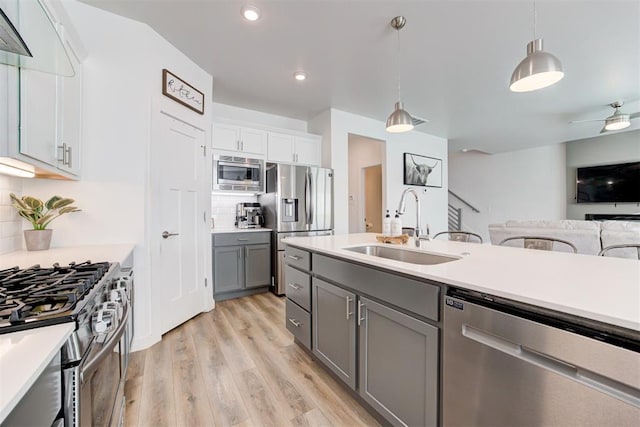 kitchen with gray cabinets, decorative light fixtures, sink, white cabinets, and stainless steel appliances