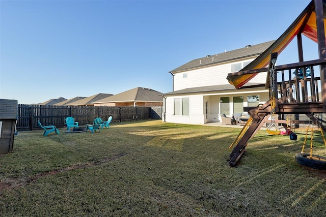 rear view of property with a yard, a playground, and an outdoor fire pit