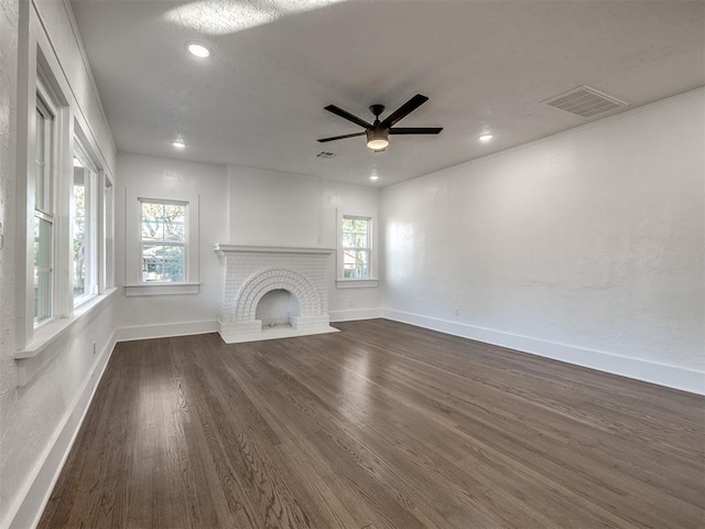 unfurnished living room featuring ceiling fan, dark hardwood / wood-style flooring, and a brick fireplace