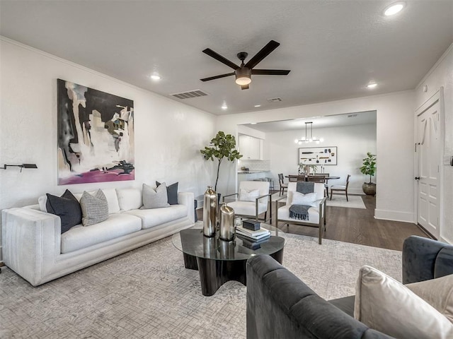 living room with crown molding, visible vents, wood finished floors, and recessed lighting