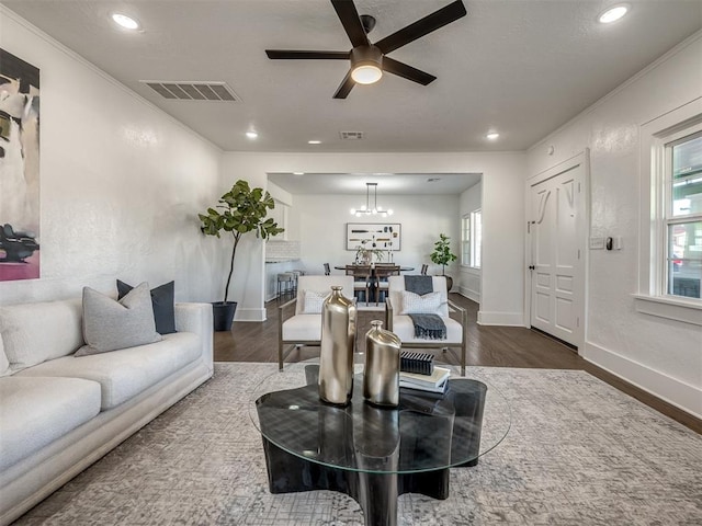 living area featuring baseboards, dark wood-style flooring, visible vents, and crown molding