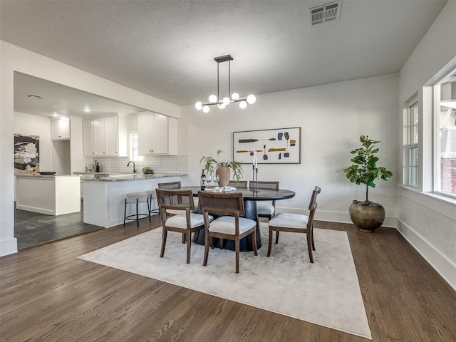 dining room with baseboards, visible vents, a chandelier, and dark wood-style flooring