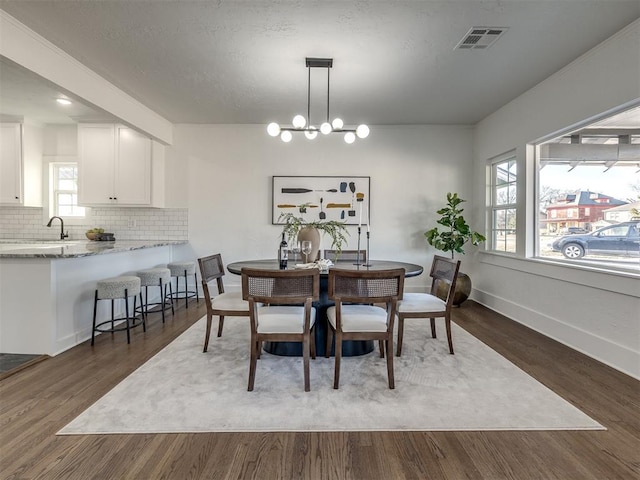 dining space with baseboards, visible vents, a chandelier, and dark wood-style flooring