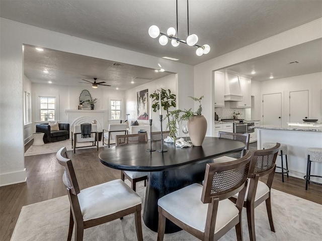 dining room featuring a ceiling fan, a fireplace, baseboards, and wood finished floors