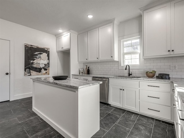 kitchen with stainless steel dishwasher, white cabinets, a kitchen island, a sink, and light stone countertops