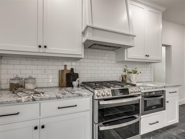 kitchen with stainless steel appliances, white cabinets, premium range hood, and light stone counters