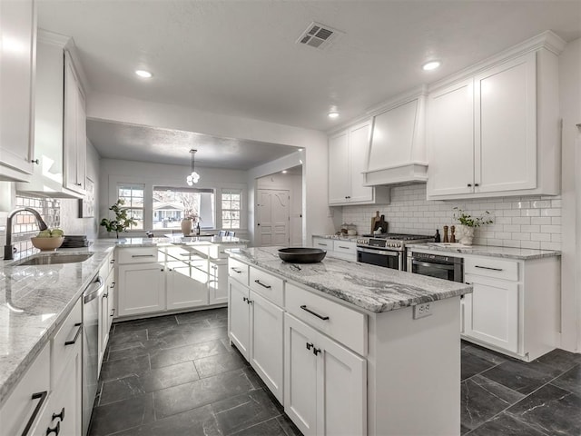 kitchen with a sink, white cabinetry, hanging light fixtures, appliances with stainless steel finishes, and a center island