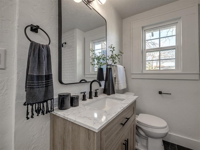 full bath with baseboards, a textured wall, vanity, and toilet