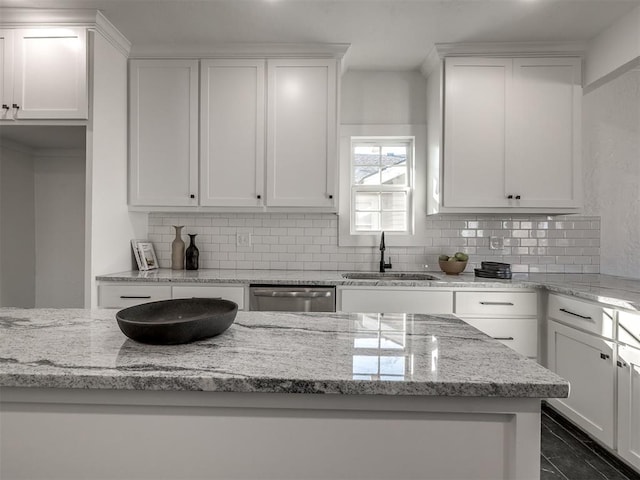 kitchen featuring stainless steel dishwasher, a sink, and white cabinetry