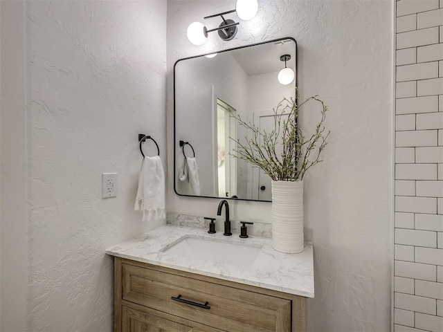 bathroom featuring a textured wall and vanity