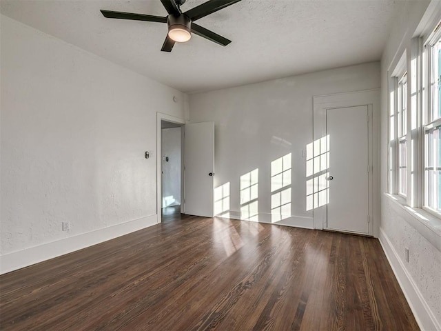 spare room featuring ceiling fan, baseboards, dark wood-style flooring, and a textured wall