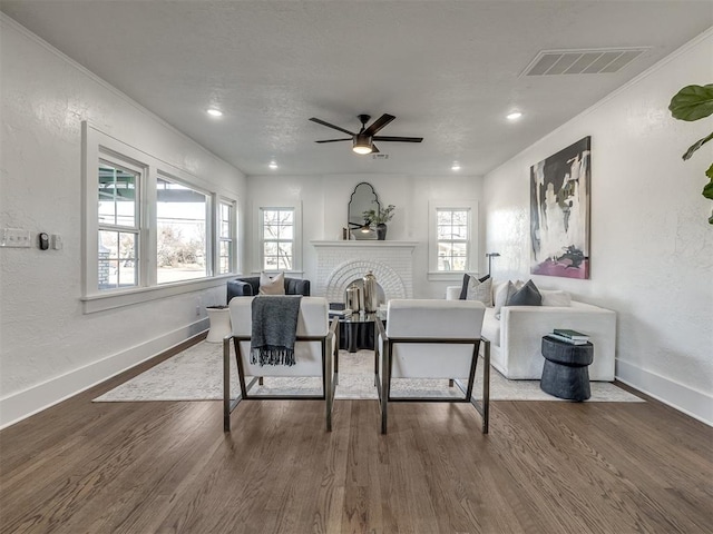 living area with a fireplace, wood finished floors, visible vents, and baseboards