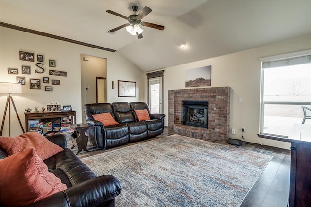 living room with hardwood / wood-style flooring, vaulted ceiling, a brick fireplace, and a wealth of natural light