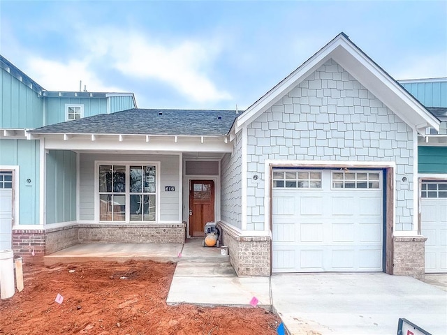 view of front of home with an attached garage, driveway, a shingled roof, and a porch