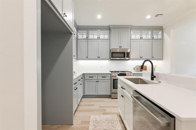 616 Montauk Way, Edmond, OK 73034 - kitchen featuring light wood-style flooring, a sink, appliances with stainless steel finishes, visible vents, and an island with sink