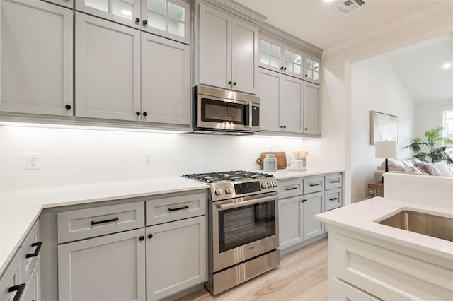 616 Montauk Way, Edmond, OK 73034 - kitchen with tasteful backsplash, light wood-style floors, appliances with stainless steel finishes, light countertops, and visible vents