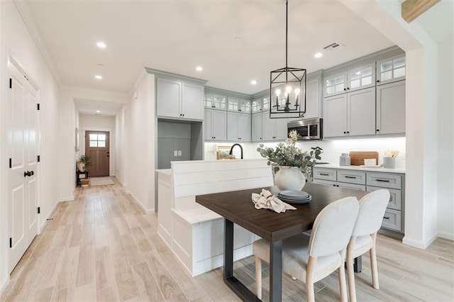 616 Montauk Way, Edmond, OK 73034 - kitchen featuring stainless steel microwave, gray cabinets, light wood-style floors, and glass insert cabinets