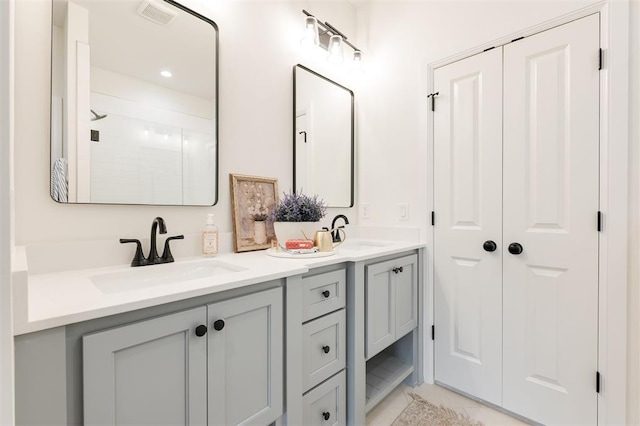 616 Montauk Way, Edmond, OK 73034 - bathroom featuring a tile shower, double vanity, a sink, and visible vents