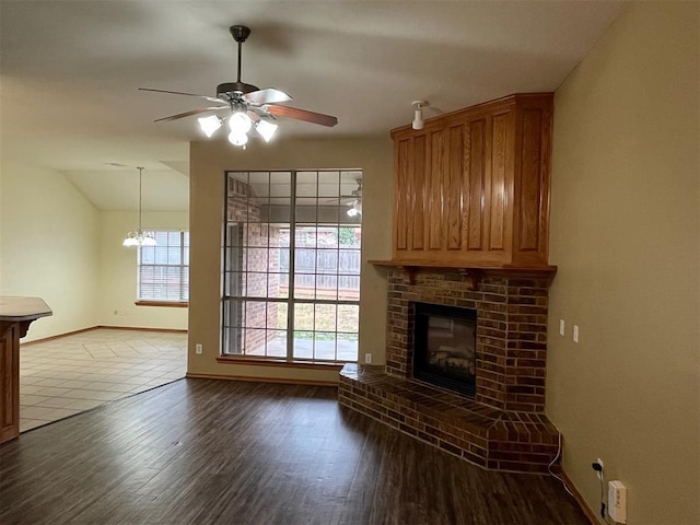 unfurnished living room featuring ceiling fan, wood-type flooring, a fireplace, and vaulted ceiling