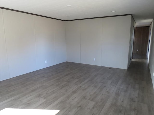 empty room featuring crown molding and hardwood / wood-style flooring