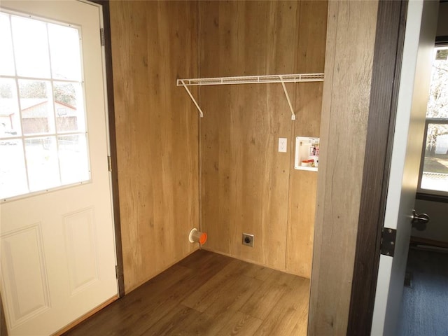 washroom with hardwood / wood-style floors, hookup for a washing machine, hookup for an electric dryer, and wood walls