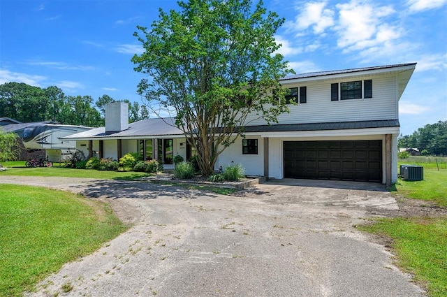 view of front of house featuring cooling unit, a garage, and a front yard