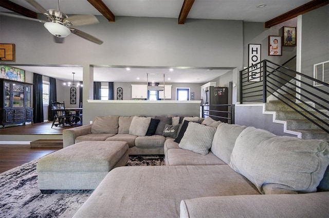 living room featuring wood-type flooring, ceiling fan with notable chandelier, and beam ceiling