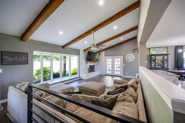 living room with vaulted ceiling with beams, ceiling fan, a brick fireplace, dark wood-type flooring, and french doors