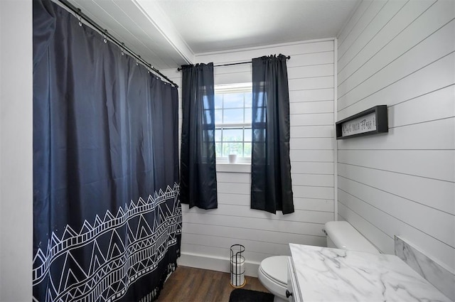 bathroom featuring vanity, hardwood / wood-style floors, wooden walls, and toilet