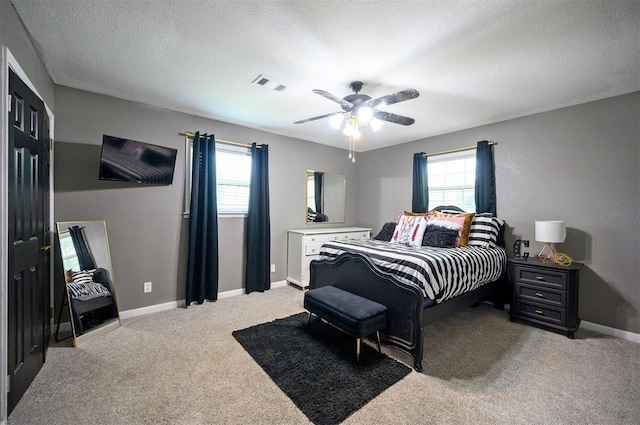 bedroom featuring multiple windows, ceiling fan, carpet flooring, and a textured ceiling