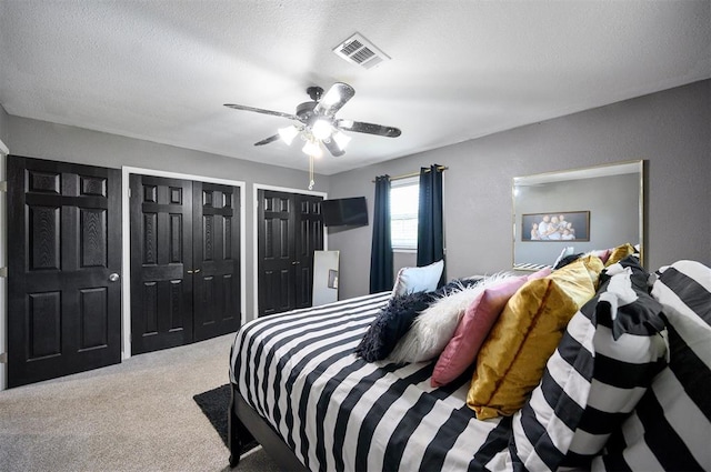 bedroom featuring a textured ceiling, multiple closets, and carpet flooring