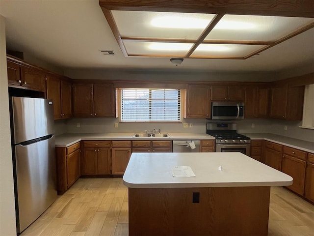 kitchen featuring a center island, appliances with stainless steel finishes, sink, and light hardwood / wood-style floors