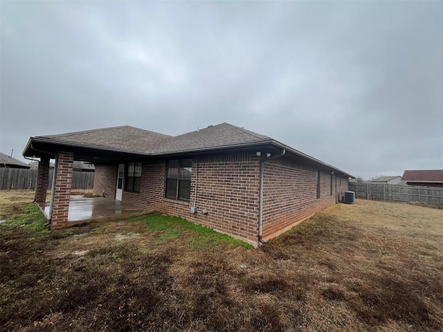 view of side of property featuring a patio, cooling unit, and a lawn