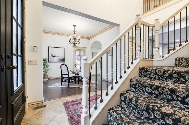 tiled foyer with an inviting chandelier and crown molding