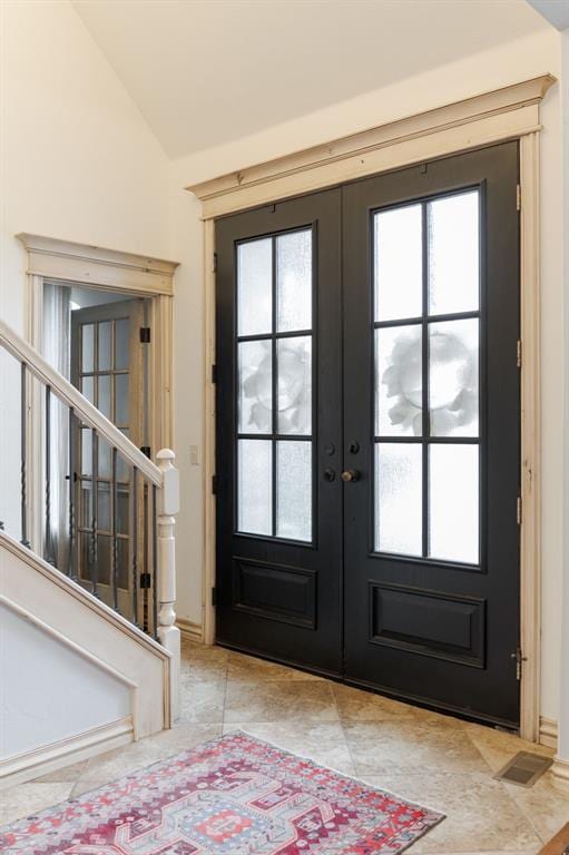 interior space featuring light tile patterned floors, vaulted ceiling, and french doors