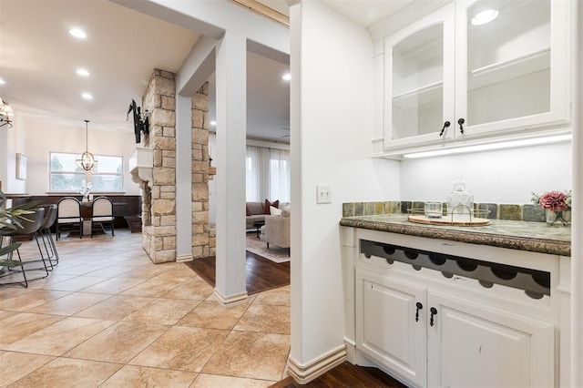 bar with white cabinetry, dark stone countertops, pendant lighting, and light tile patterned floors