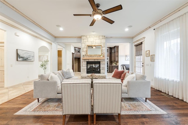 living room featuring ceiling fan, ornamental molding, a fireplace, and dark hardwood / wood-style flooring