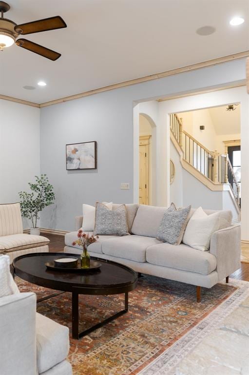 living room with wood-type flooring, ornamental molding, and ceiling fan