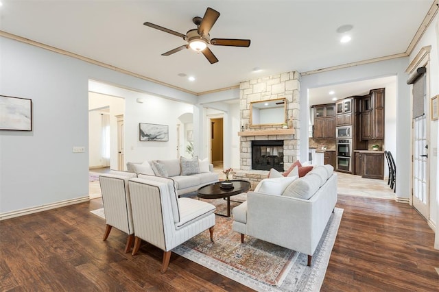 living room featuring ornamental molding, a stone fireplace, and dark hardwood / wood-style floors