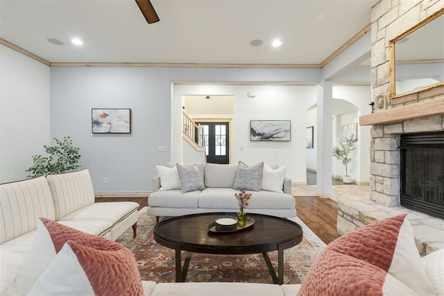 living room with a fireplace, ornamental molding, and light wood-type flooring